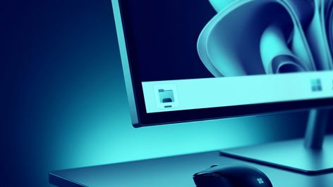 Primer plano de un monitor con la interfaz de Windows 11, mostrando el icono del Explorador de archivos en la barra de tareas sobre un escritorio iluminado en tonos azules.