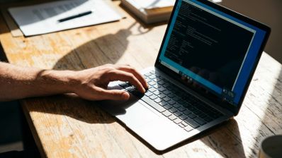 Persona utilizando un ordenador portátil en el que se muestra una ventana de la consola de comandos de Windows con información técnica sobre el sistema.