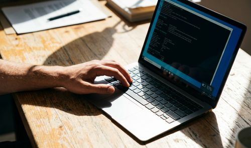 Persona utilizando un ordenador portátil en el que se muestra una ventana de la consola de comandos de Windows con información técnica sobre el sistema.