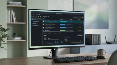 Interfaz del software qBittorrent 5.3 mostrada en un monitor de escritorio con varios archivos en descarga y gráficas de tráfico.