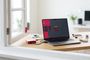 Ordenador portátil ejecutando el sistema operativo Raspberry Pi Desktop junto a una placa Raspberry Pi en su carcasa oficial sobre un escritorio de madera.