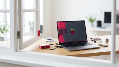 Ordenador portátil ejecutando el sistema operativo Raspberry Pi Desktop junto a una placa Raspberry Pi en su carcasa oficial sobre un escritorio de madera.