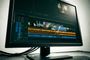Interfaz de un editor de vídeo en un monitor de sobremesa con líneas de tiempo y ondas de audio.