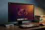 Monitor de ordenador en un escritorio mostrando el escritorio de Ubuntu con un fondo de pantalla de una raya estilizada.
