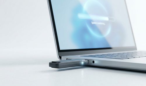 Memoria USB conectada al puerto lateral de un ordenador portátil que muestra una barra de carga en pantalla.