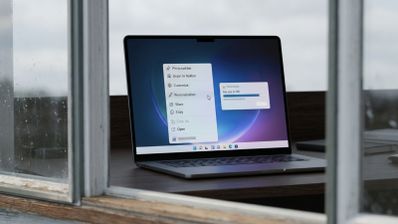 Ordenador portátil mostrando el menú contextual de Windows con opciones de personalización y una barra de progreso de descarga de 5 GB.