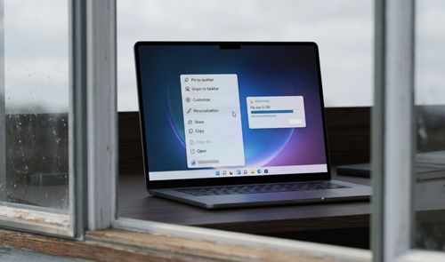 Ordenador portátil mostrando el menú contextual de Windows con opciones de personalización y una barra de progreso de descarga de 5 GB.