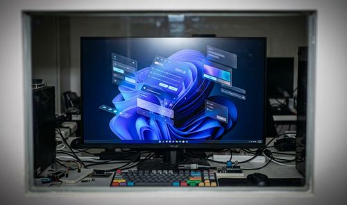 Monitor de ordenador en un entorno de desarrollo que muestra diversos elementos de la interfaz de usuario de Windows 11 flotando sobre el escritorio.